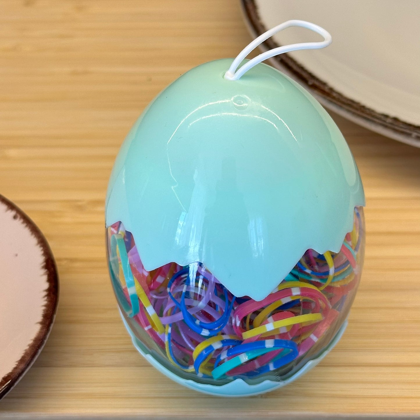 Spalvotos su baltais brūkšniukais guminės gumytės žaliame kiaušinio dėkle